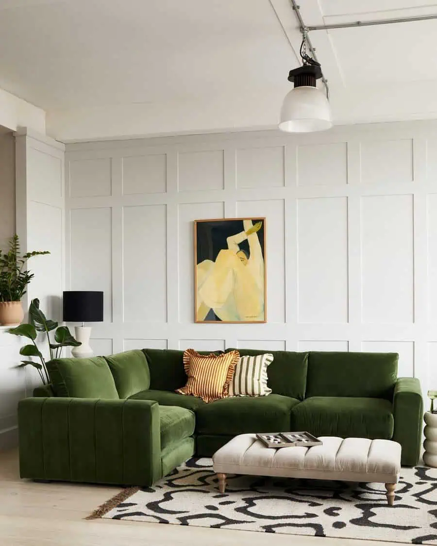 Living room corner with a green sectional sofa, abstract art, plants, and a patterned rug.