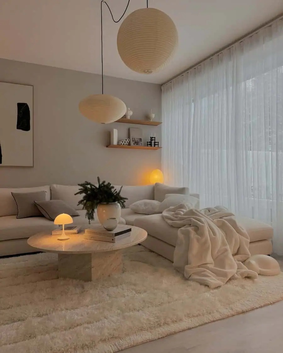 Minimalist living room corner with neutral tones, a cozy sofa, paper lanterns, and soft lighting.