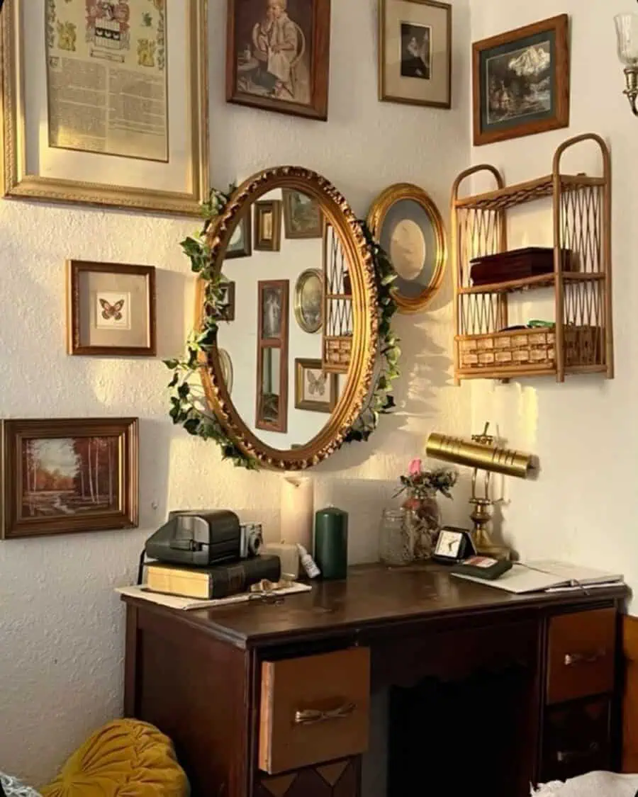 Vintage living room corner with a wooden desk, gold-framed mirror, and eclectic wall art.