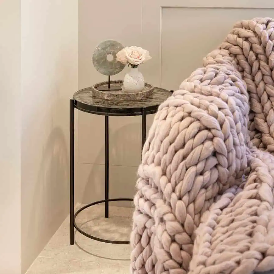 Living room corner with a chunky knit throw, modern side table, and minimalist decor accents.