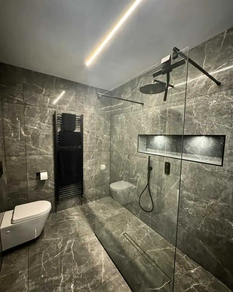 Luxury bathroom with marble-look grey tiles, walk-in shower, and black matte fixtures.