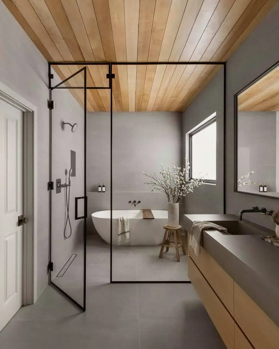 Modern bathroom with matte grey tiles, a freestanding tub, and natural wood accents for a minimalist and serene atmosphere.