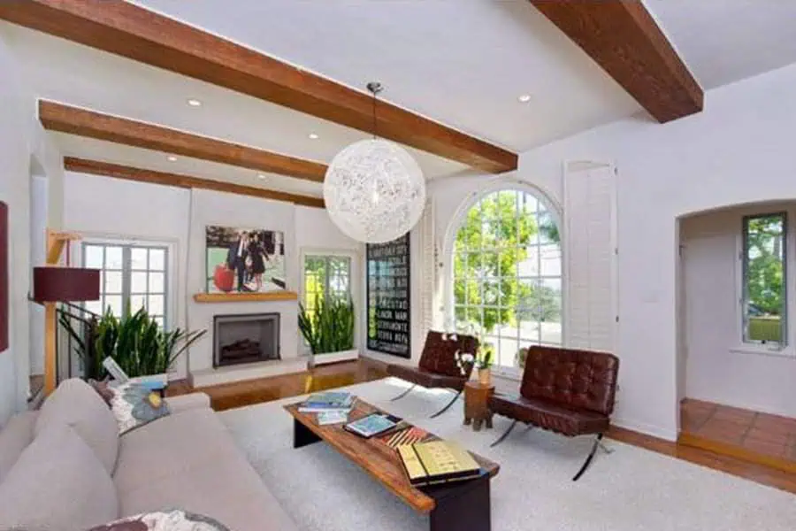 Spanish-style living room with exposed wooden beams, arched window, and modern furniture.