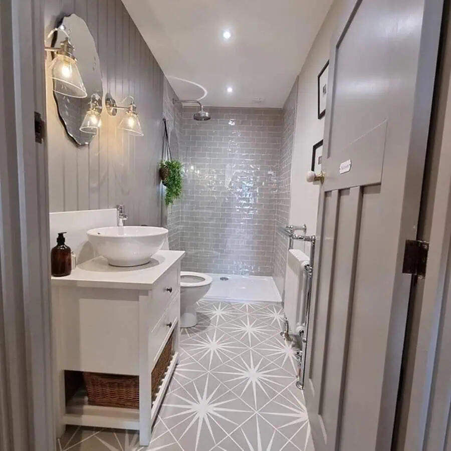 Bathroom with patterned grey floor tiles, white vanity, and subway-tiled shower walls.