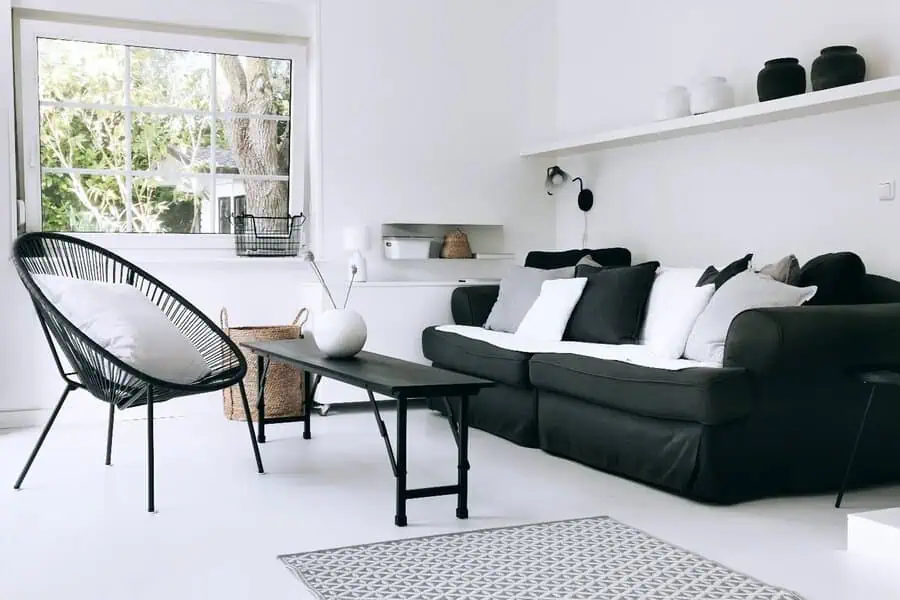 Scandinavian living room with black sofa, modern chair, white walls, and minimalist decor.