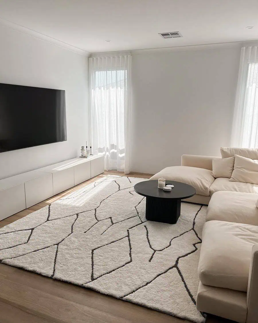 Minimalist Scandinavian living room with cream sofa, black coffee table, and geometric rug.