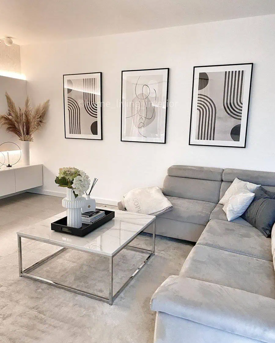 Scandinavian living room with abstract wall art, gray sofa, and a modern glass coffee table.