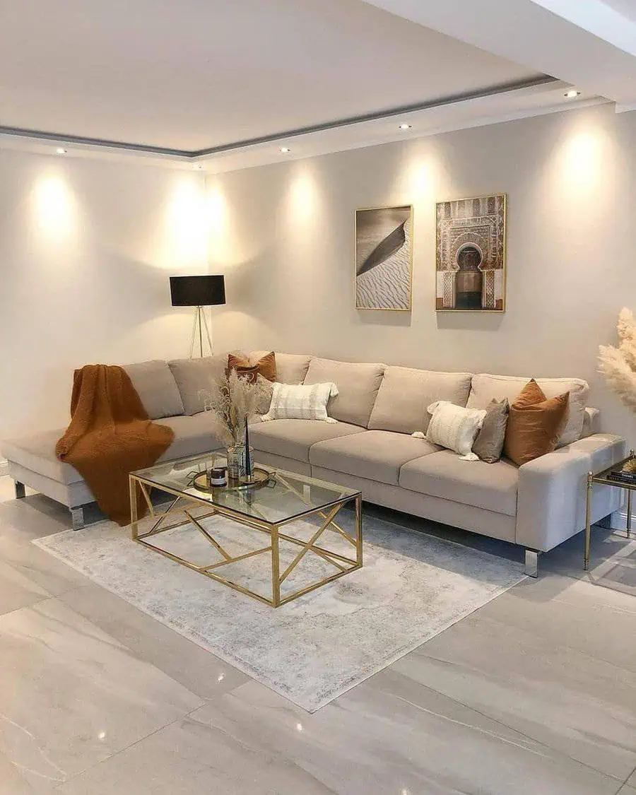 Scandinavian living room with beige sectional sofa, gold-accented coffee table, and warm lighting.