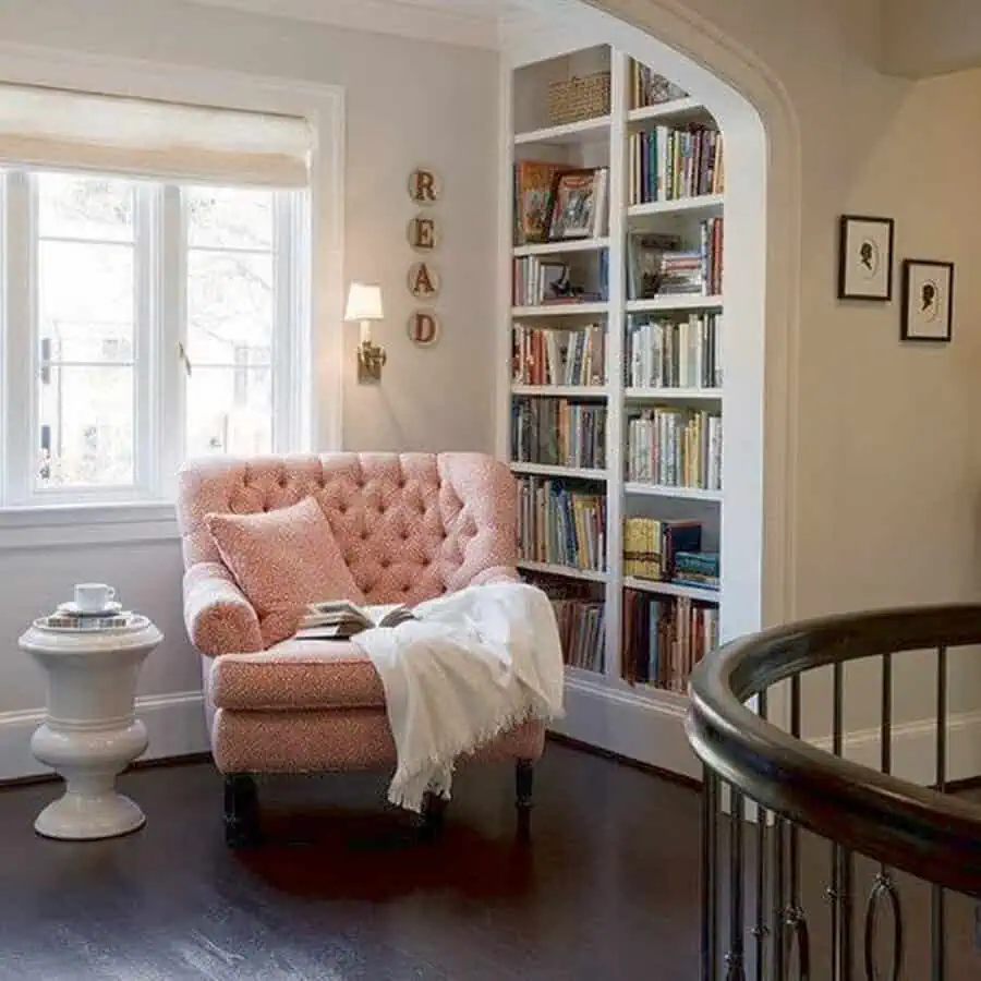 Scandinavian reading nook with a pink armchair, built-in shelves, and natural light.