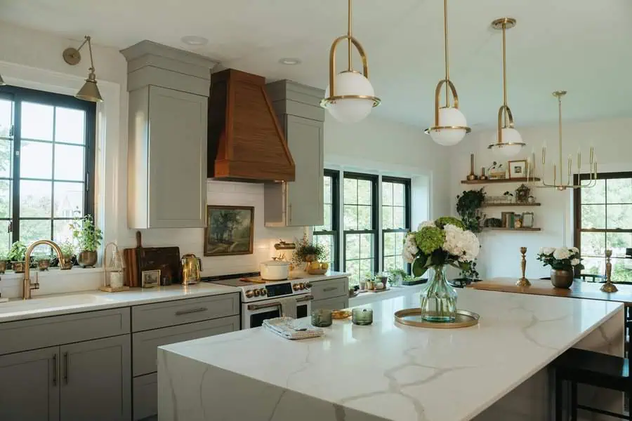 Scandinavian kitchen with marble countertops, wood accents, and gold fixtures.