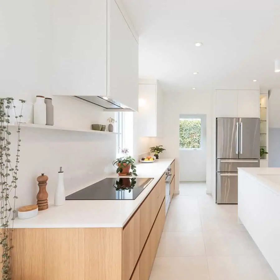 Minimalist Scandinavian kitchen with white cabinetry, wooden accents, and natural lighting.