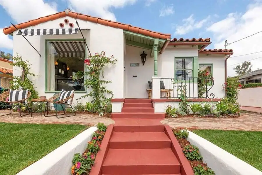 Single-story Spanish-style house with white stucco walls, red tile roof, and a cozy front porch.