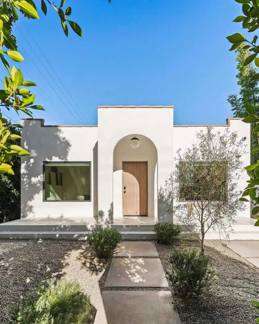 Small Spanish-style house with white stucco walls, arched entryway, and simple garden.