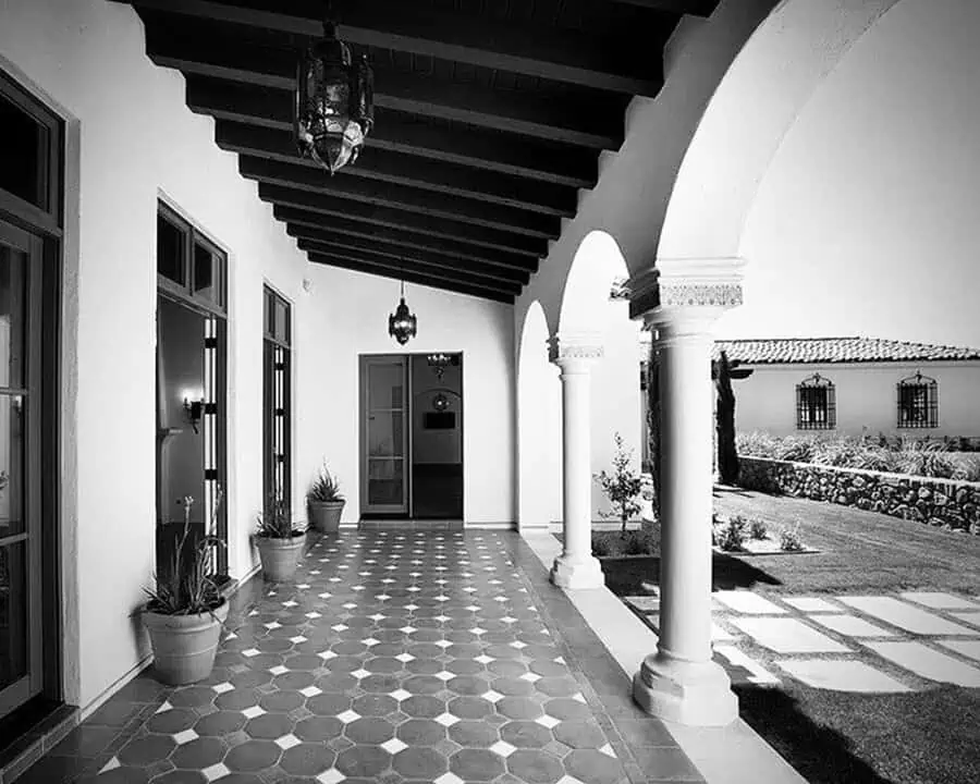 Spanish colonial-style home with arched columns, tiled flooring, and decorative hanging lanterns.