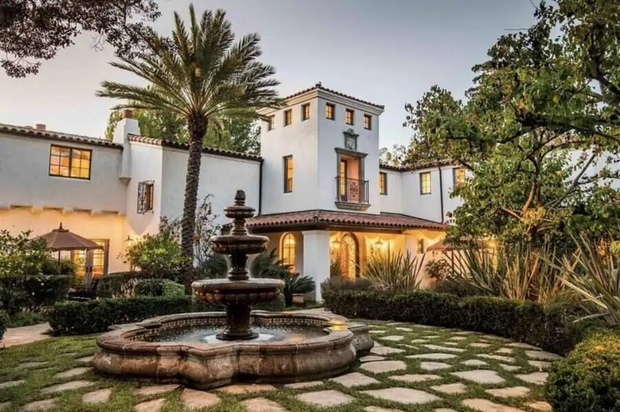 Colonial Spanish-style home with a red tile roof, central tower, courtyard, and decorative fountain.