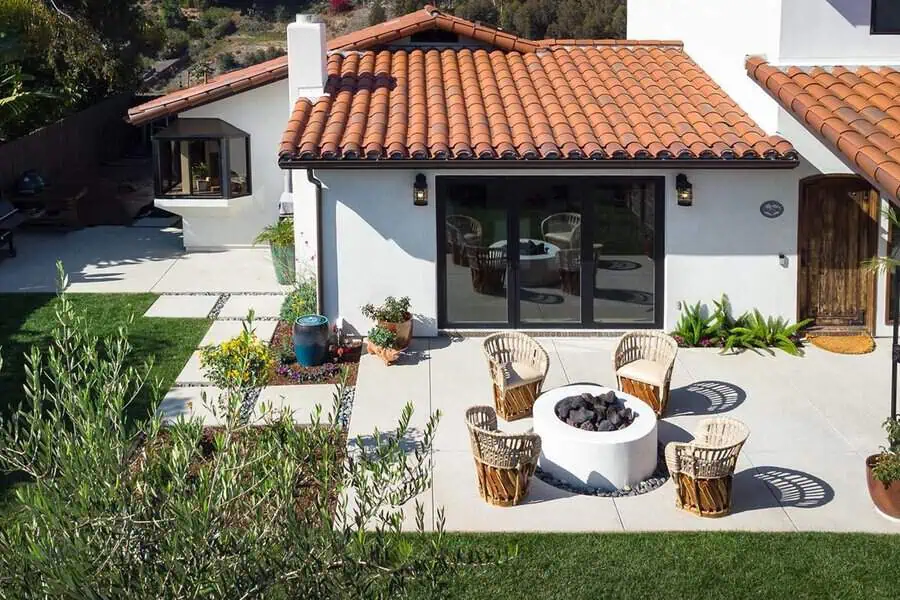 This Spanish-style home features a red tile roof, white stucco walls, and a cozy outdoor space with a fire pit.