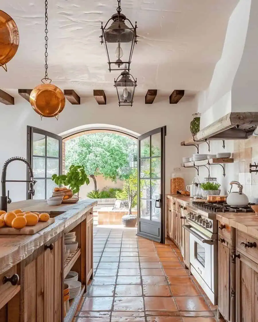 This Spanish-style kitchen boasts rustic wooden cabinetry, terracotta tiles, and arched doors opening to a lush outdoor space.