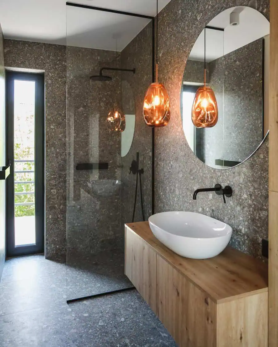 Stone-look grey floor tiles paired with textured walls and a warm wooden vanity for a cozy, natural vibe.