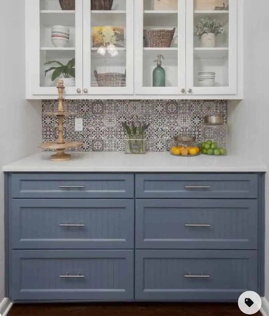 Compact kitchen with blue lower cabinets, white upper cabinets, and patterned tile backsplash.