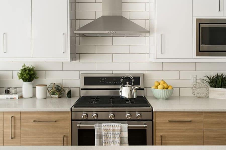 Modern kitchen with white upper cabinets, wood lower cabinets, and subway tile backsplash.