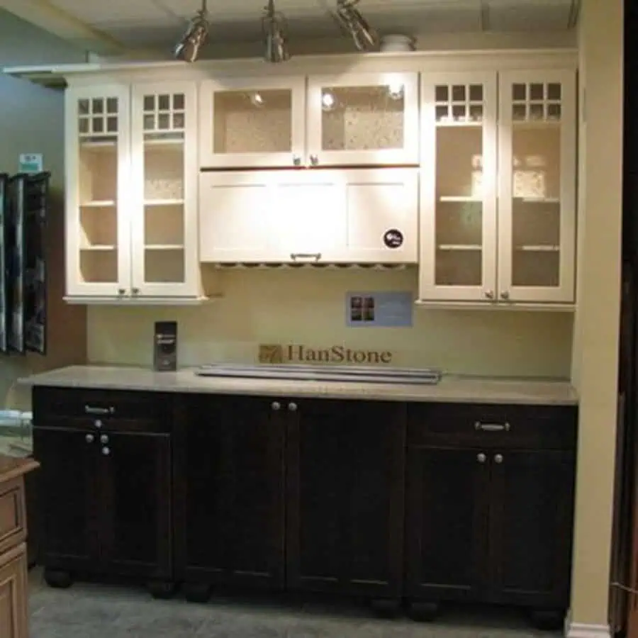 Kitchen with white glass-paneled upper cabinets, dark wood lower cabinets, and spotlighting.