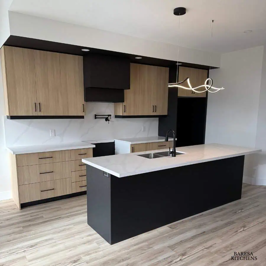 Contemporary kitchen with light wood cabinets, black island, and modern white countertops.