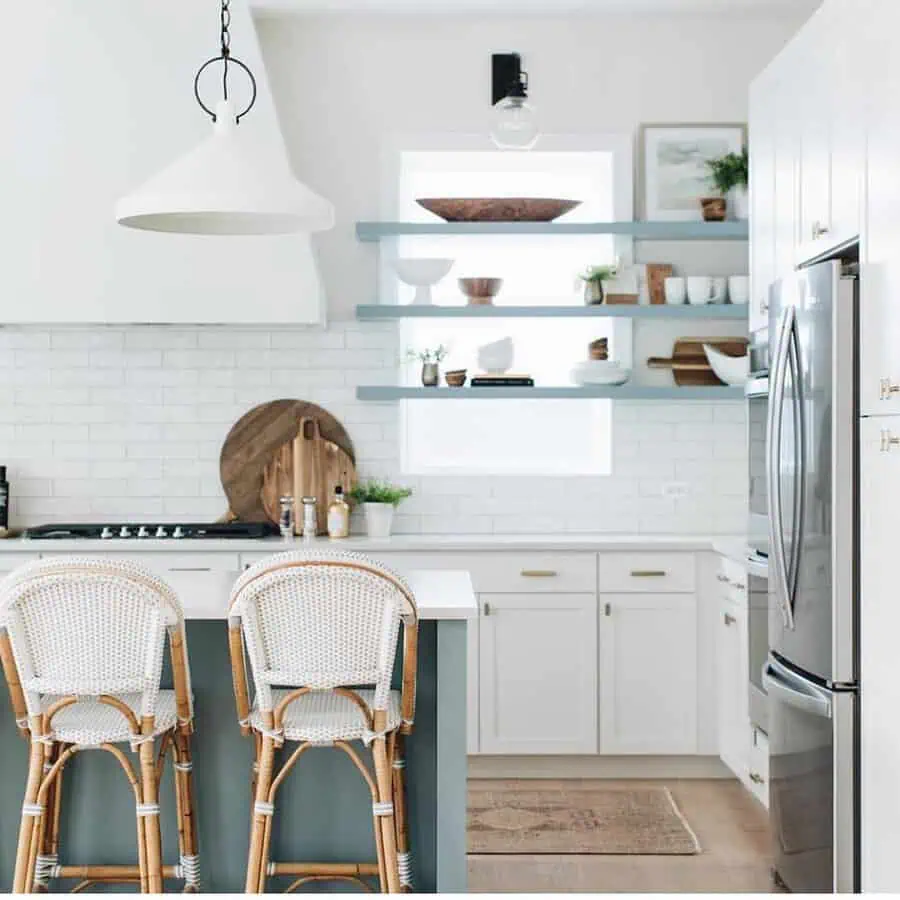 Bright kitchen with white cabinets, blue open shelves, and rattan bar stools.