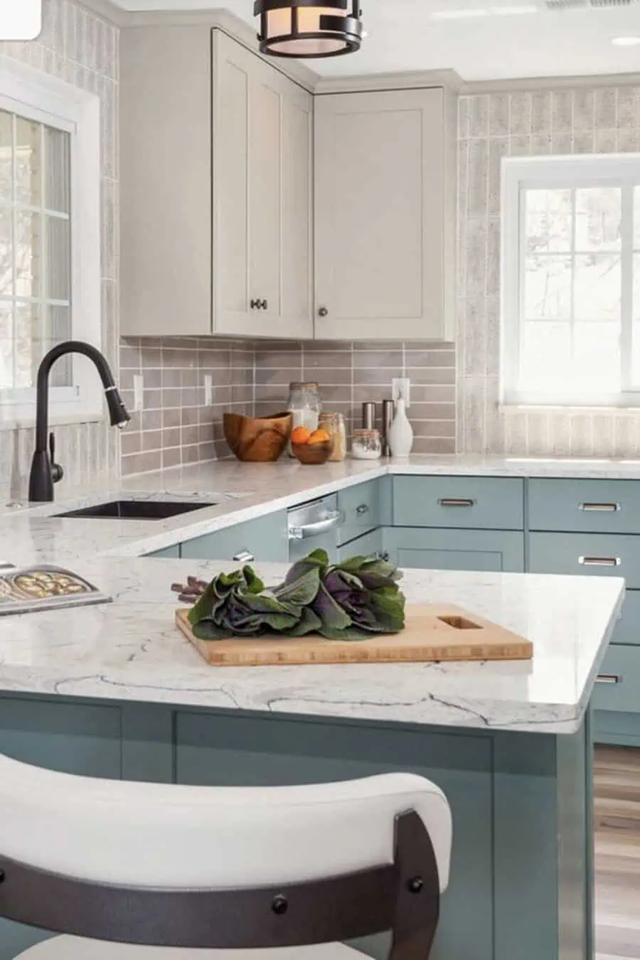 Transitional kitchen with beige upper cabinets, blue lower cabinets, and marble countertops.