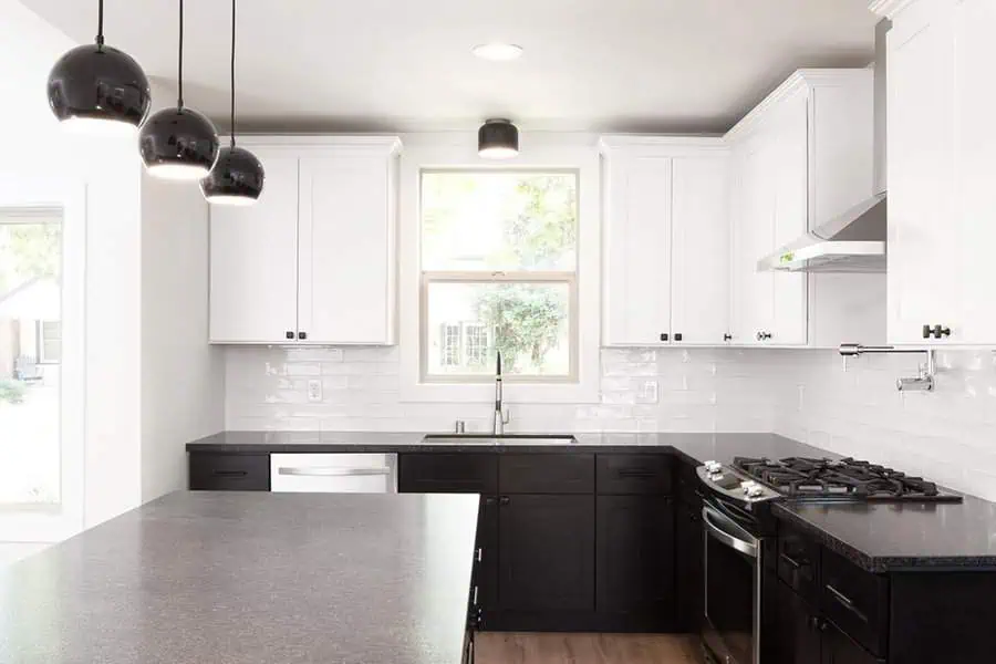 Contemporary kitchen with white upper cabinets, black lower cabinets, and modern pendant lights.