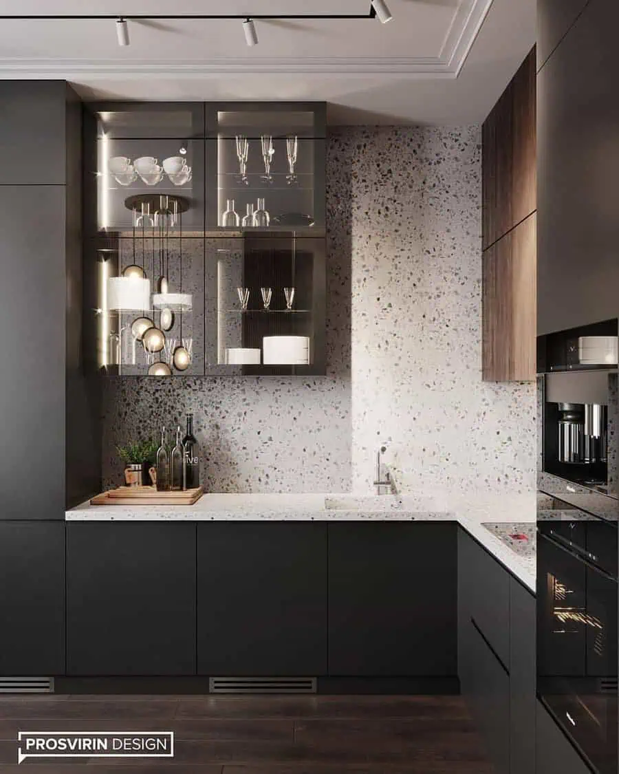 Modern kitchen with matte black cabinets, terrazzo backsplash, and illuminated glass shelves.