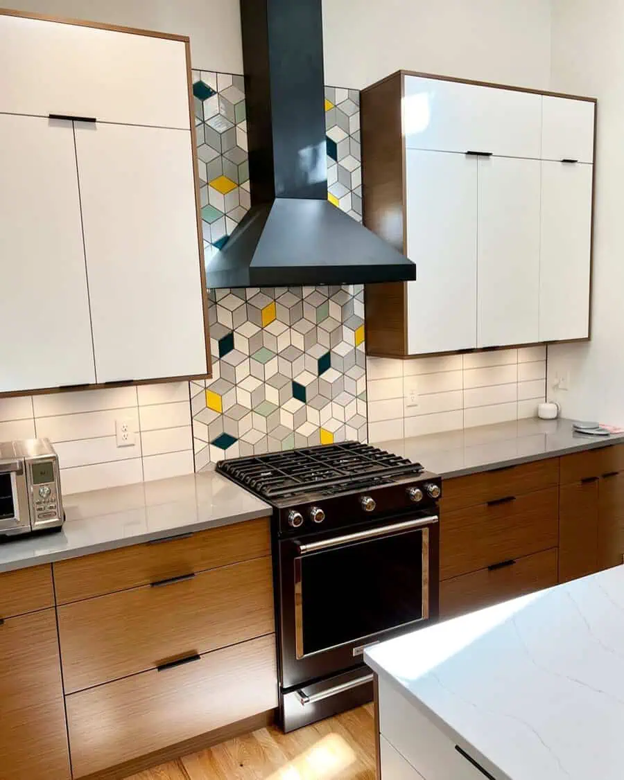 Two-tone kitchen with white upper cabinets, wood lowers, and a geometric tile backsplash.