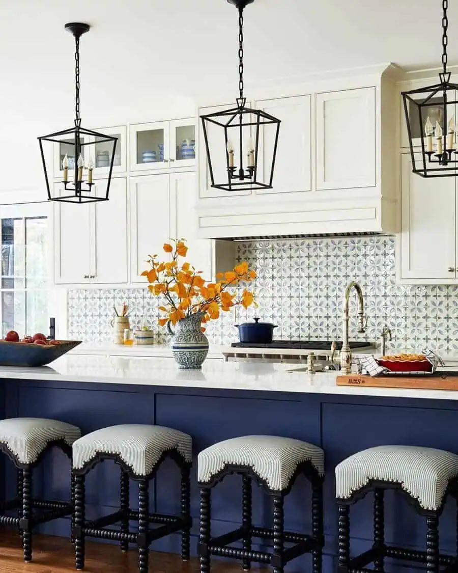 Elegant two-tone kitchen featuring navy blue lower cabinets, white upper cabinets, a patterned backsplash, and stylish pendant lights.