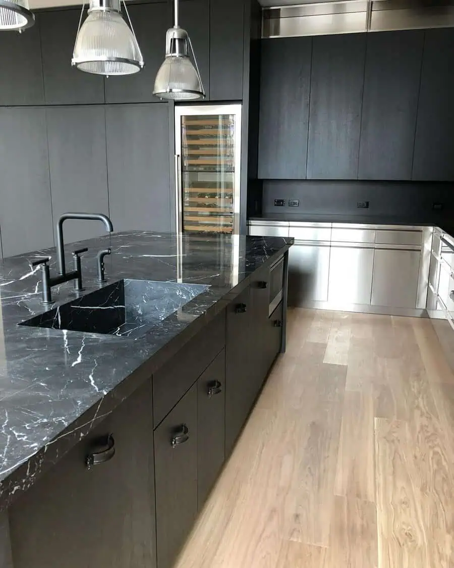 A sleek, contemporary kitchen featuring matte black cabinets, stainless steel accents, and a luxurious black marble island countertop.