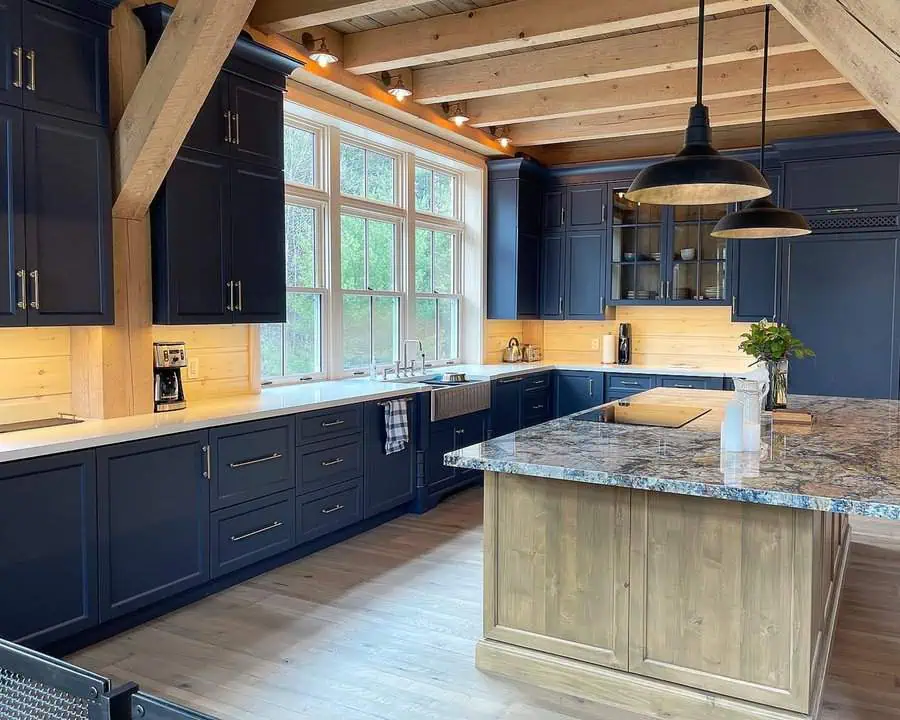 Rustic kitchen with navy blue cabinets, wooden beams, and a large island with a granite countertop.