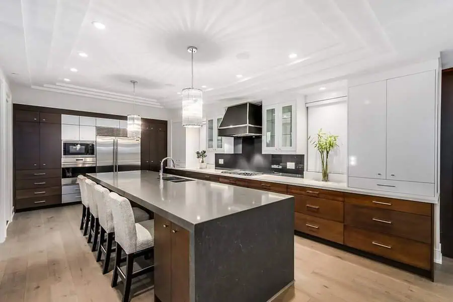 Modern kitchen with dark wood lower cabinets, white upper cabinets, and a large island.