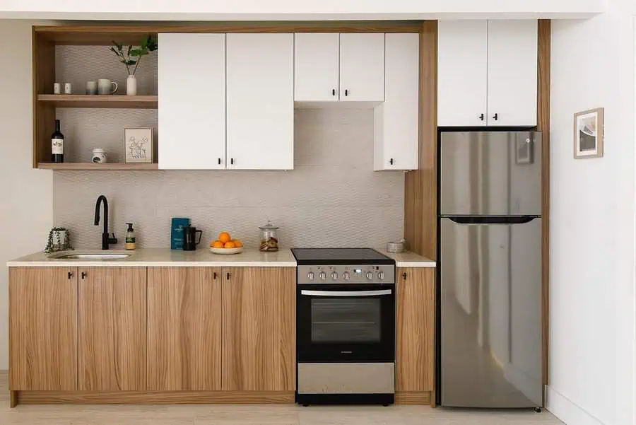 Small kitchen with white upper cabinets, wood lower cabinets, and stainless steel appliances.