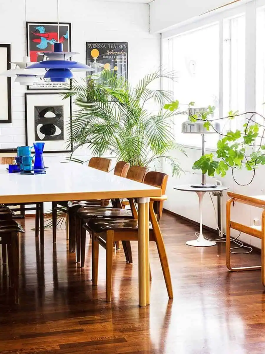 1960s Scandinavian dining room with minimalist furniture, bold lighting, and lush indoor plants.