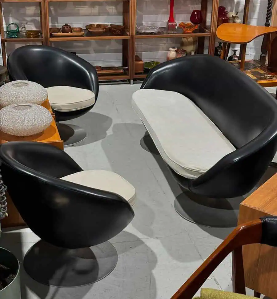 1960s retro lounge set with black and white curved seating, vintage decor, and mid-century modern style.