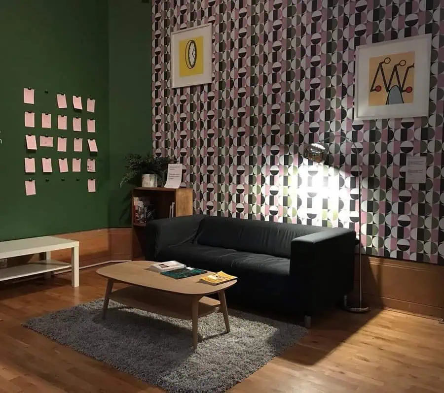 1960s-inspired living room with bold geometric wallpaper, dark green walls, and retro decor.