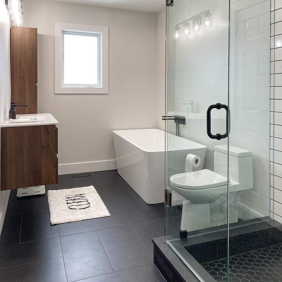 Black and white bathroom with glass shower, freestanding tub, and modern wood vanity.