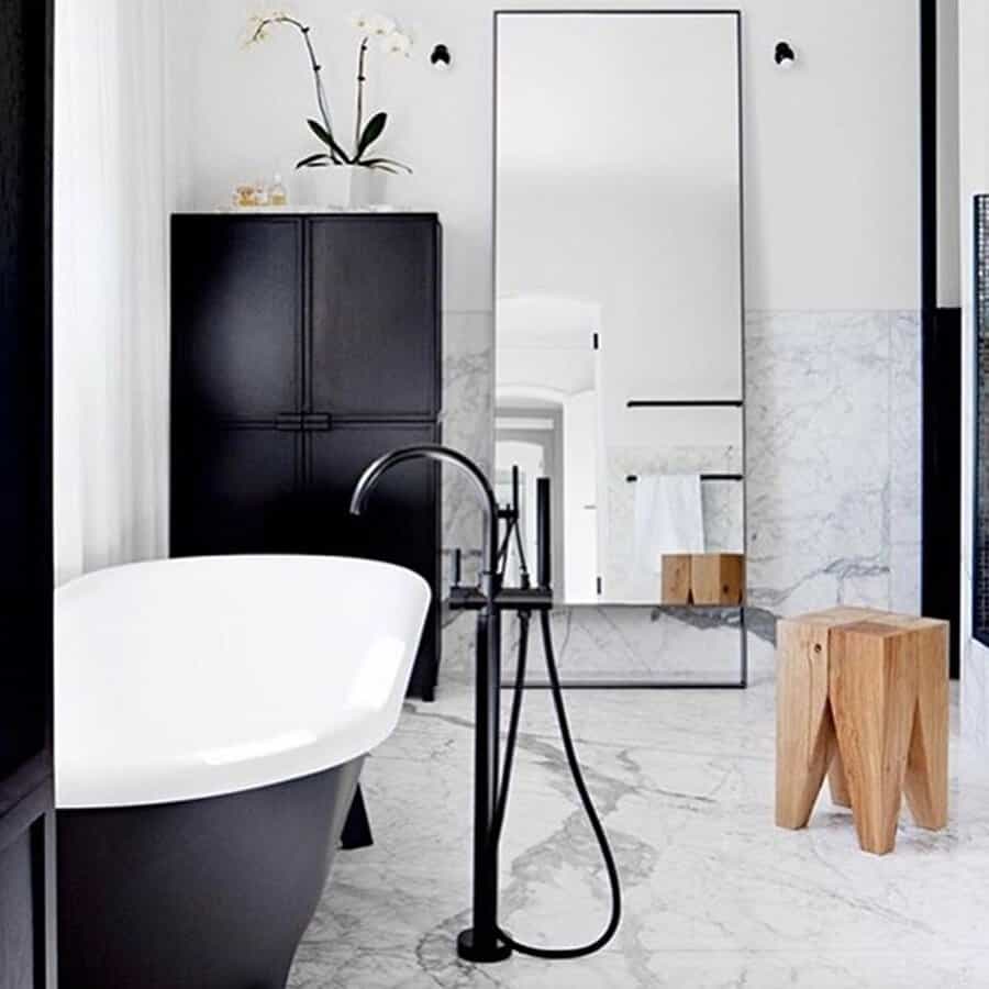Modern bathroom with matte black fixtures, glossy white walls, and a freestanding tub.