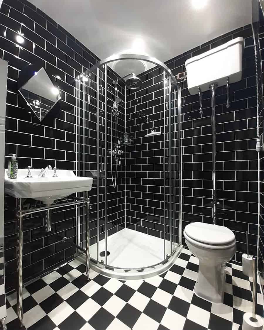Black and white bathroom with Art Deco lighting, glossy subway tiles, and a checkered floor.