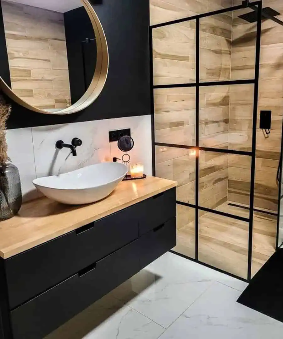 Modern black and wood bathroom with a glass shower, vessel sink, and warm ambient lighting.