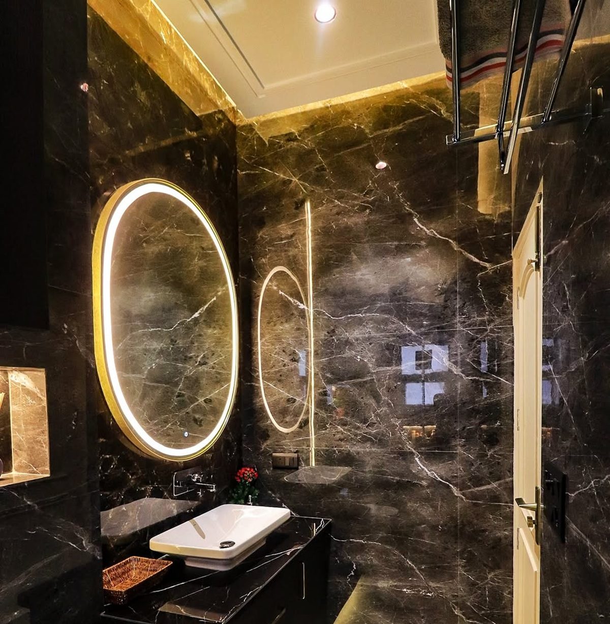 Luxury black bathroom with marble walls, backlit mirrors, and a sleek floating vanity.