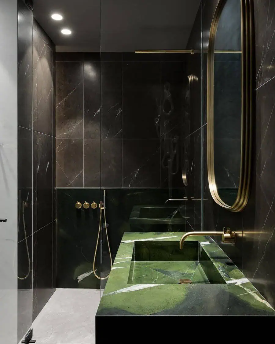 Luxury black bathroom with green marble sink, gold fixtures, and a sleek modern mirror.