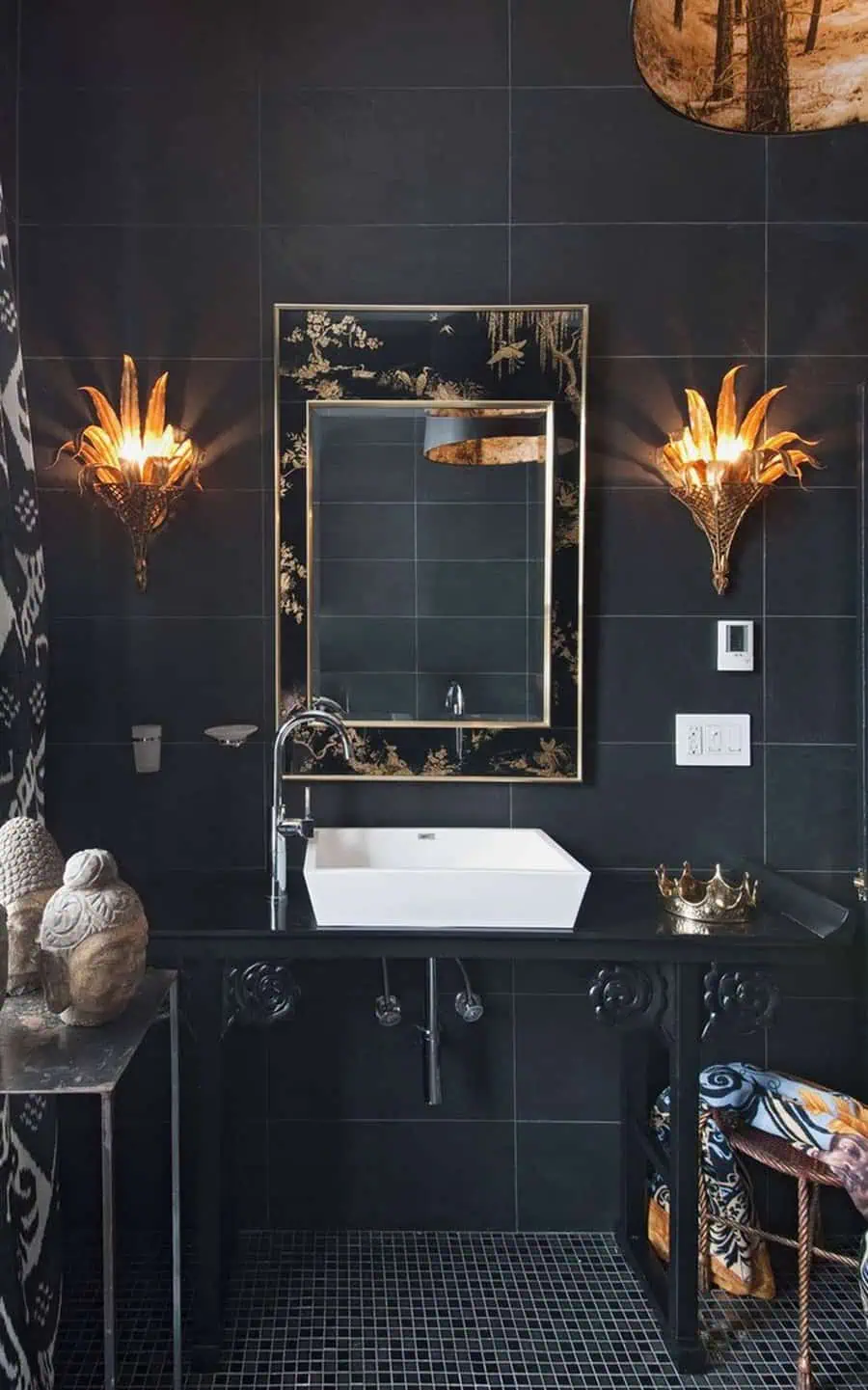 Elegant black bathroom with gold accents, ornate mirror, and dramatic wall sconces.