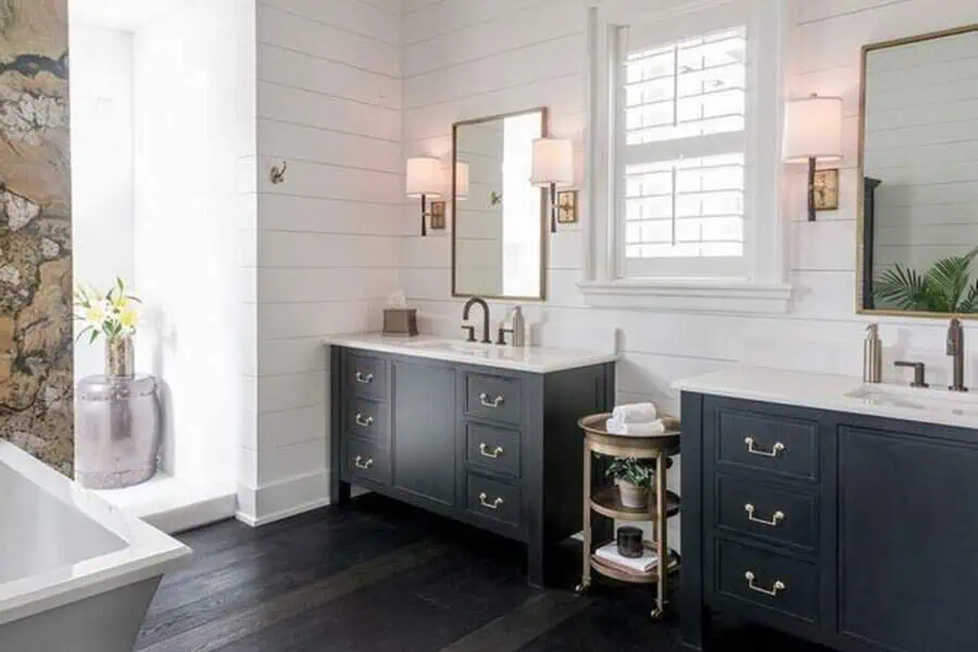 Modern farmhouse bathroom with black vanities, gold hardware, and white shiplap walls.