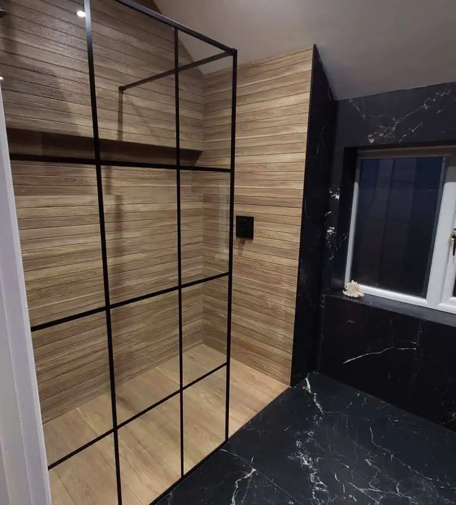 Modern black bathroom with wood accents, a glass shower, and a sleek floating vanity.