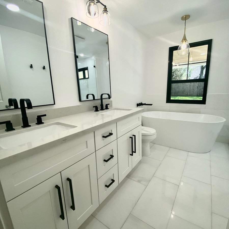 Black and white bathroom with black window trim, double vanity, and freestanding bathtub.