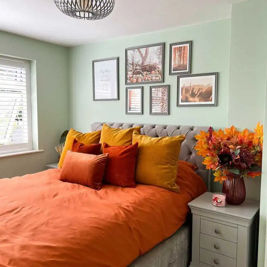 Bold bedding with orange and mustard pillows, adding a vibrant contrast to a cozy orange bedroom.